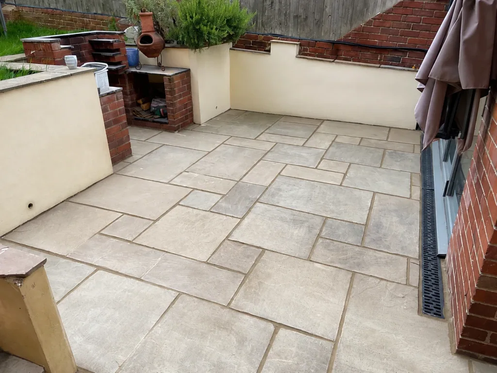 Sandstone paved courtyard laid in a random pattern, enclosed by rendered walls, brick piers and a built-in brick barbecue.